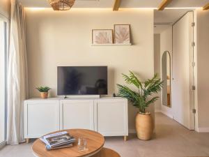 ein Wohnzimmer mit Fernseher und Tisch in der Unterkunft MOSCATELL - Terraza privada con encanto Mediterráneo in Jalón