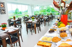 a dining room with tables and chairs with food on them at BR Suítes Hotel in Navegantes