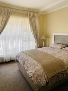 a bedroom with a large bed and a large window at Khayalethu in Kempton Park