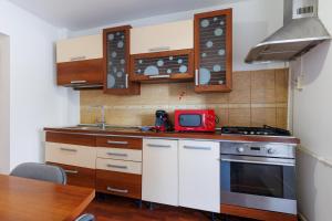 a kitchen with white cabinets and a red microwave at Central Corner Craiova in Craiova