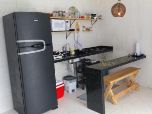 a kitchen with a black refrigerator and a counter at Vila Negreiros Serra Negra Casa 4 in Bezerros
