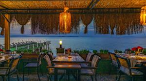 a restaurant with tables and chairs and a view of the ocean at Kayalar Blue Beach Hotel in Sazlı