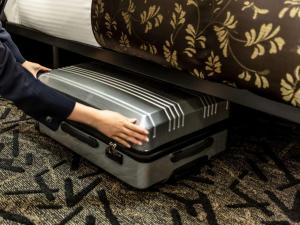 a person is holding a suitcase under a bed at APA Hotel Akihabara Ekimae in Tokyo