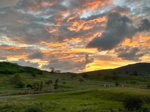 a field with a sunset in the sky at Vila Negreiros Serra Negra Casa 4 in Bezerros
