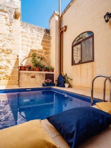 a swimming pool in a house with a brick wall at Tal-Bambinu Boutique B&B in Xagħra