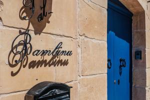 a building with a blue door and a mailbox at Tal-Bambinu Boutique B&B in Xagħra