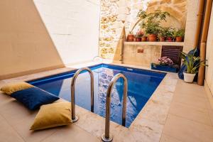 a swimming pool with a pillow on the floor at Tal-Bambinu Boutique B&B in Xagħra