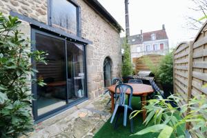 a small patio with a wooden table and chairs at La grange de Louise in La Chapelle-Taillefert