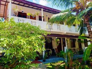 a house with a palm tree in front of it at Niluka Rest in Kataragama