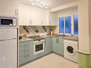 a kitchen with white cabinets and a washer and dryer at Desigual apartamento con 3 AC in Gandía