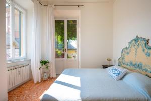 a bedroom with a bed with a blue headboard and a window at Villa Questa - Oasi sommersa nel Verde in Chiavari