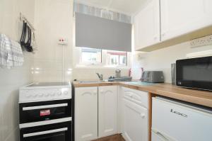 a small kitchen with a stove and a microwave at 13 Hillside in Bude +9 photos