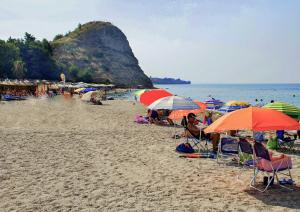a group of people sitting on a beach with umbrellas at Isminis country house in Vergia +6 photos
