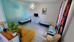 a living room with a yellow couch and a chair at Apartament przy zlocie in Borne Sulinowo +4 photos