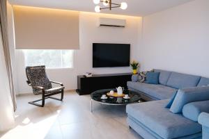 a living room with a blue couch and a tv at Aquarama Suites in Iraklitsa