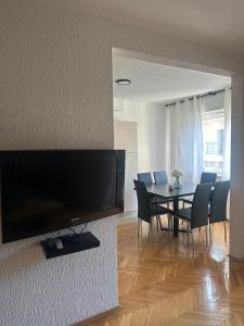 a dining room with a table and a television on a wall at Apartman Seven Kaštel Stari in Kaštela