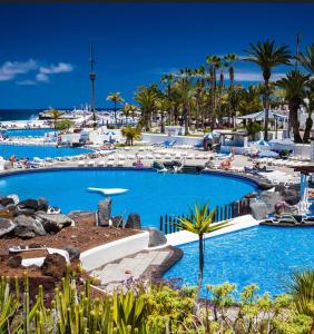 una grande piscina accanto a una spiaggia con palme di Casa Suami a Puerto de la Cruz