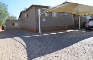 a large umbrella in a parking lot in front of a building at JayLa SELFCATERING ACCOMMODATION in Windhoek