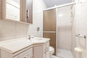 ein Badezimmer mit Waschbecken, Toilette und Dusche in der Unterkunft Espaçosa Casa a 200 Metros da Praia de Bombas in Bombas + 13 Fotos