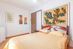 ein Schlafzimmer mit einem Bett mit einem großen Gemälde an der Wand in der Unterkunft Espaçosa Casa a 200 Metros da Praia de Bombas in Bombas
