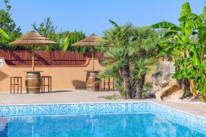 a swimming pool in front of a resort with umbrellas at Villa Relais ALGHERO -Country Villa with Pool in Alghero