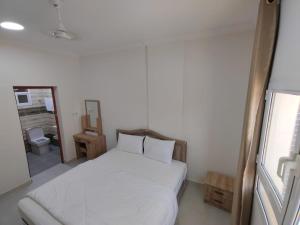 a bedroom with a white bed and a mirror at Al Anwar Building Luxury in Salalah