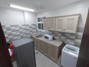 a small kitchen with a sink and a refrigerator at Al Anwar Building Luxury in Salalah