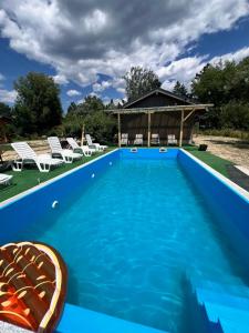 a blue swimming pool with chairs and a gazebo at The Frog Glamping in Horezu