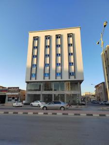 a tall building with cars parked in a parking lot at Al Anwar Building Luxury in Salalah