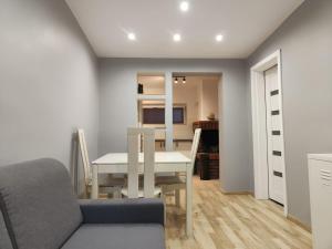 a dining room with a white table and a couch at Domek w centrum in Okuninka