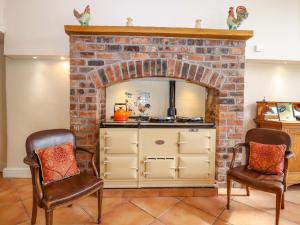 a kitchen with a brick fireplace and two chairs at Rob Roy Apartment in Stirling