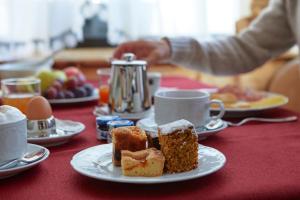 a table topped with plates of pastries and cups of coffee at Hotel Garni dello Sportivo in Madonna di Campiglio