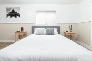 a bedroom with a large white bed with two tables at Cozy Millcreek Home SLC in Millcreek