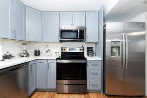a kitchen with white cabinets and a stainless steel refrigerator at Cozy Millcreek Home SLC in Millcreek