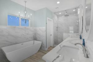a white bathroom with a tub and a sink at Near Beach Large Home Sleeps 22 BBQ Soaking Tub in Bolivar Peninsula +38 photos