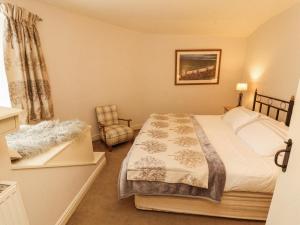 a bedroom with a bed and a chair at Corner Cottage in Carnforth