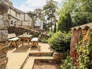 a garden with a wooden table and a stone wall at Corner Cottage in Carnforth