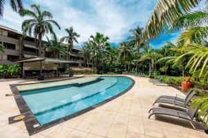 克瓦拉海滩Kewarra Beach Coastal Retreat 2BR Apt with Pool and BBQ的度假村内的游泳池,带椅子和棕榈树