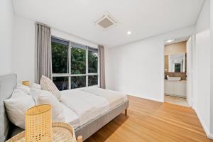 パースにあるScarborough Escape, New 3Br Suite,141のベッドと大きな窓のある白い寝室