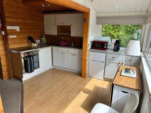 a kitchen with white cabinets and a table with a lamp at Caban Enfys in Trawsfynydd
