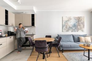 eine Frau steht in der Küche eines Wohnzimmers in der Unterkunft Porto Letnica Apartments with Gym & Parking by Lion Apartments in Danzig