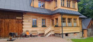 a wooden house with a staircase and chairs in front of it at Schronisko Stary Młyn in Zakopane