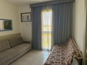 a living room with a couch and a window at Apartamento Reserva do Sahy - Condomínio Aldeia dos Reis in Mangaratiba