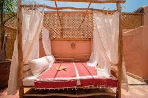 eine Verandaschaukel mit einer rot-weißen Decke in der Unterkunft Riad Le Soleil de Bahia in Marrakesch