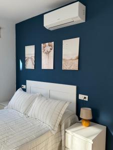 a bedroom with a blue wall with a bed and pictures at Break Room in Playa Honda