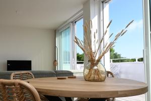 a dining room table with a vase of flowers at Casa del Rops, luxury apartment, two bathrooms and roof terrace, near the beach in Cadzand