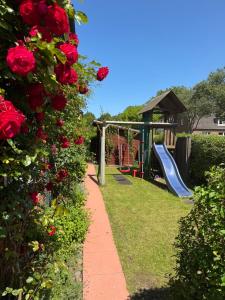 a garden with a playground with a slide and roses at Landjägerhaus am Südstrand - Wohnung 1 + 3 in Wyk auf Föhr