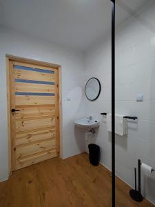 a bathroom with a wooden door and a sink at Pensjonat Jaśmin in Ustka