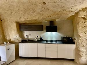 a kitchen with white cabinets in a stone wall at IL Nido nella Roccia in Matera