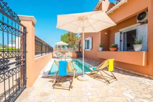 un patio avec une table, des chaises et un parasol dans l'établissement Villa Mandola by Villa Plus, à Acharavi